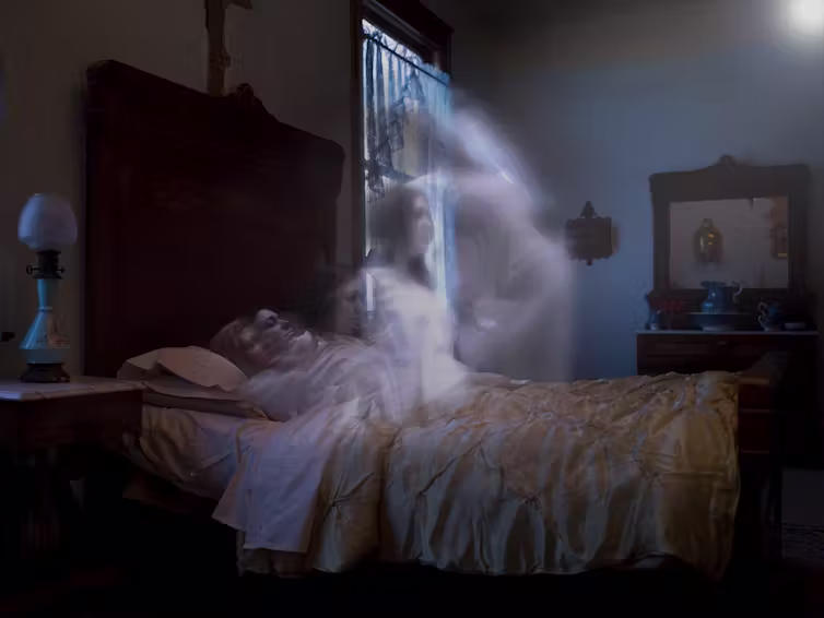 woman lying in bed with transparent image of woman rising away from her reclined body